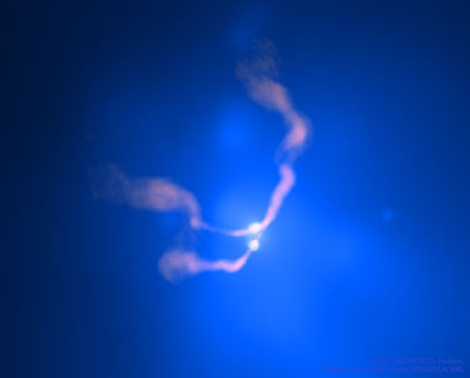 Opisywane zdjęcie pokazuje dwa jasne źródła blisko centrum
pobliskiej galaktyki. Obiekt nazywany jest 3C 75. Uważa się, że
dwa jasne źródła to dwie czarne dziury zbliżające się wolno po
spirali do siebie. Wyziewy sprawiają, że zarys Słońca zdaje się
falować. Zobacz opis. Po kliknięciu obrazka załaduje się wersja
 o największej dostępnej rozdzielczości.