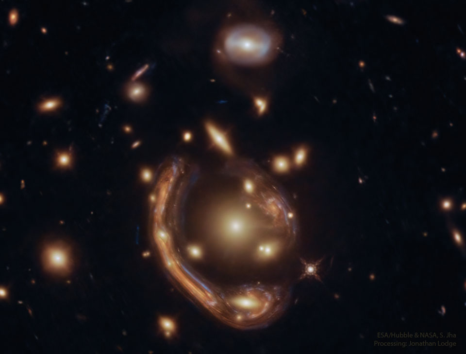Opisywane zdjęcie pokazuje odległą galaktykę zniekształconą
do olbrzymiego łuku wokół środka gromady galaktyk przez soczewkowanie
grawitacyjne. Zobacz opis. Po kliknięciu obrazka załaduje się wersja
 o największej dostępnej rozdzielczości.
