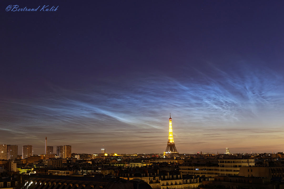 The featured image shows the Eiffel tower in Paris, France
below a wide display of glowing noctilucent clouds. 
Please see the explanation for more detailed information.