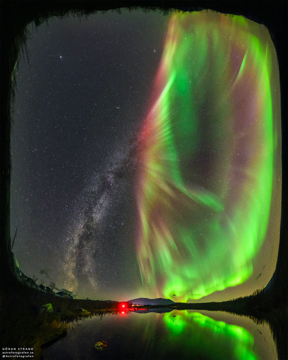Opisywane zdjęcie na pierwszym planie pokazuje jezioro
w Szwecji, a nad nim Drogę Mleczną po lewej oraz zieloną
zorzę polarną po prawej. Na piwerszy rzut oka może się wydawać,
że zorza polarna jest kwiatem wyrastającym z łodygi Drogi Mlecznej.
Zobacz opis. Po kliknięciu obrazka załaduje się wersja
 o największej dostępnej rozdzielczości.