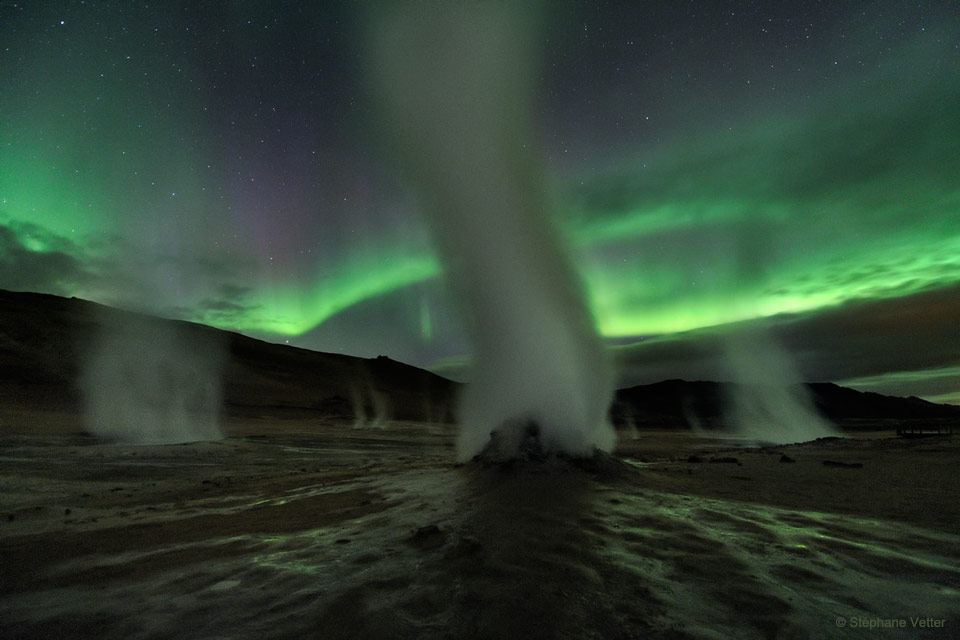 Opisywane zdjęcie pokazuje parę unoszącą się z kilku
osobnych kominów w Hverir, aktywnym geotermalnie polu na
Islandii. W tle widoczna jest zielona zorza polarna.
Zobacz opis. Po kliknięciu obrazka załaduje się wersja
 o największej dostępnej rozdzielczości.