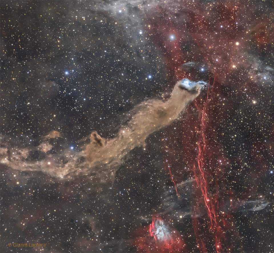 The featured image shows a long stretch of brown
dust ending in a blue glow. Along the right a gas
filament glows in red.
Please see the explanation for more detailed information.