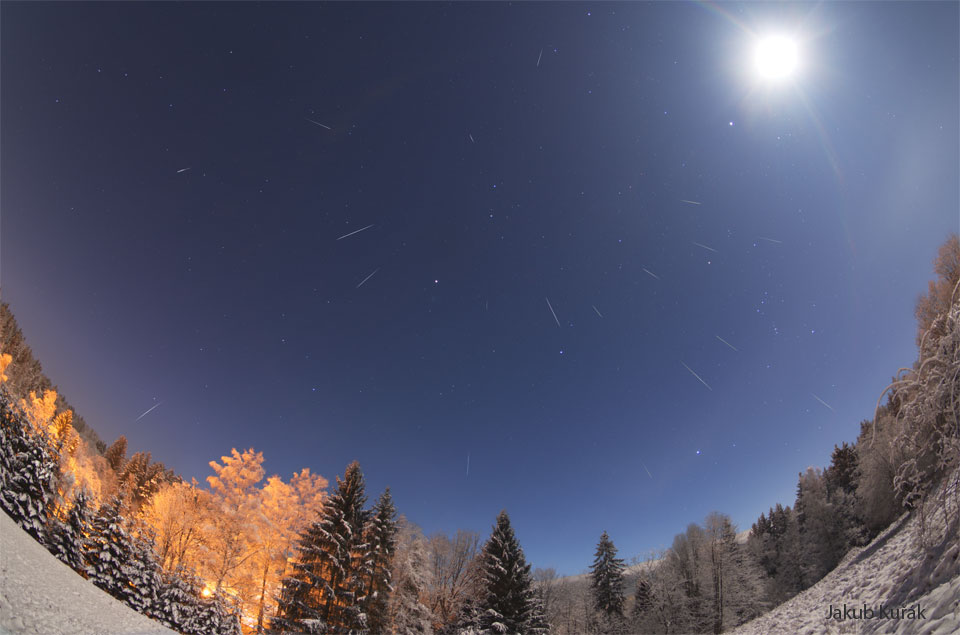 Na zdjęciu przedstawiono śnieżny krajobraz pod rozgwieżdżonym niebem.
W prawym górnym rogu widoczny jest bardzo jasny Księżyc. Wiele ze sfotografowanych
smug to meteory zarejestrowane w ciągu nocy.
Zobacz opis. Po kliknięciu obrazka załaduje się wersja
 o największej dostępnej rozdzielczości.