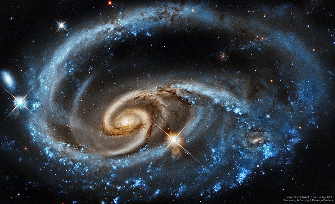 A bright galaxy with unusual blue spiral arms is shown
against a dark starfield. The outer part of the spiral 
appears as a blue ring, while the inner part appears to
have separate -- and more tan -- spiral structure. 
Więcej szczegółowych informacji w opisie poniżej.