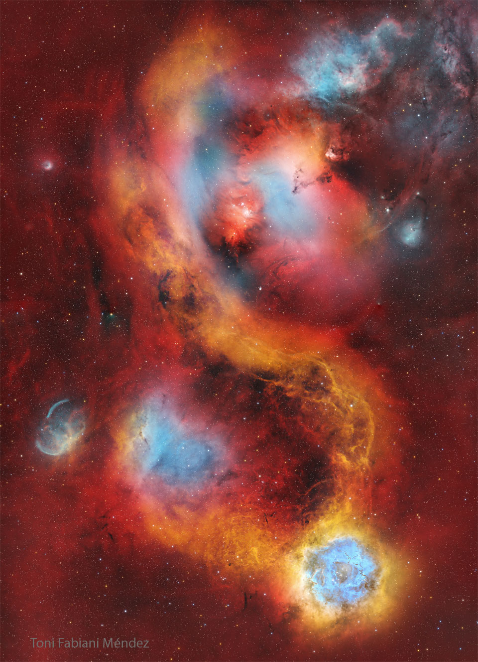 A starfield is covered with a light red glow. Several
nebulas are seen near the center. The famous Rosette nebula
appears in blue and white near the image bottom. 
Więcej szczegółowych informacji w opisie poniżej.