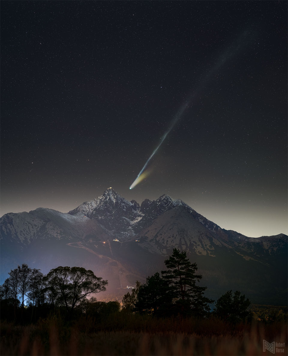 An image of the night sky over distant mountains
features a comet with long tails. One of the tails
goes nearly to the edge of the picture on the upper right.
Więcej szczegółowych informacji w opisie poniżej.