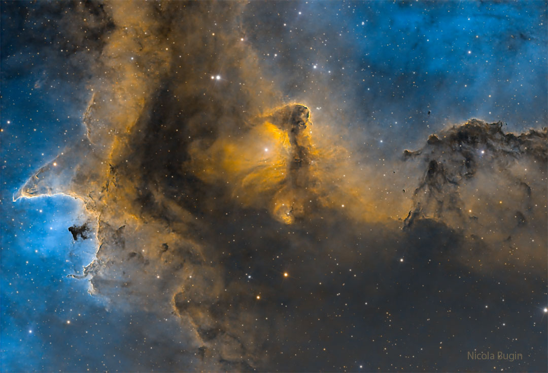 A starfield is shown with a brown and gold tinted
dust structures in front of a glowing blue gas background.
Więcej szczegółowych informacji w opisie poniżej.