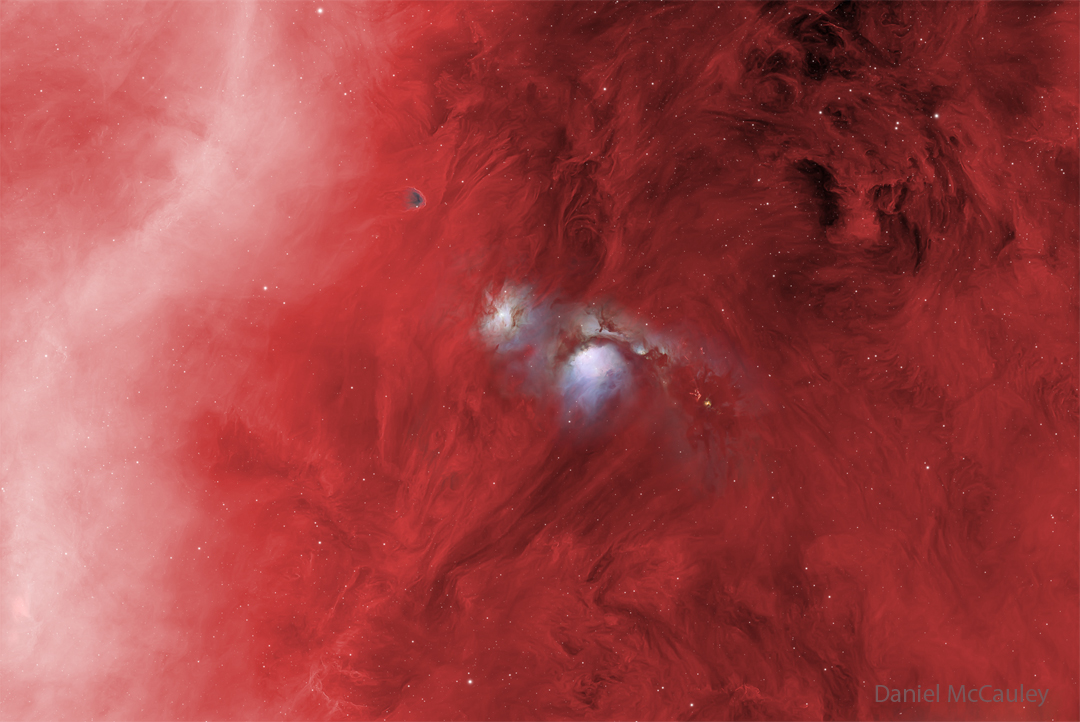 In a starfield glowing red, several features stand
out. On the right is a diffuse white band, and on the 
upper right is some dark dust. Most prominently, though,
are two blue structures in the center, one of which has
a dark band running across near the middle. 
Więcej szczegółowych informacji w opisie poniżej.