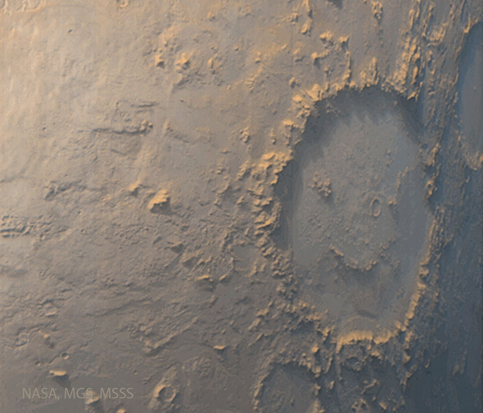 Several craters are visible on a tan surface. 
The largest crater, on the right, has internal 
markings that make it look like a winking face
with a smile. 
Więcej szczegółowych informacji w opisie poniżej.
