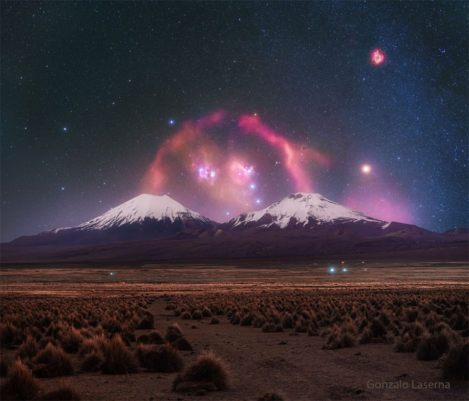 A pair of snow topped volcanoes are seen in the distance.
A background starry sky is seen behind them, with a red filamentary
nebula looping around that appears to connect the two tops 
of the volcanoes. 
Więcej szczegółowych informacji w opisie poniżej.